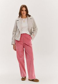 Světlá šedá herringbone sako s dvěma velkými knoflíky, bílý top, růžové klučičí kalhoty a zvířecí vzorovaný slip-on obuv.