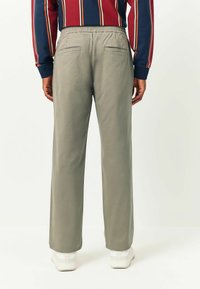 Light grey, elastic-waist pants with a smooth texture, featuring two back pockets and a straight-leg design, paired with white footwear.