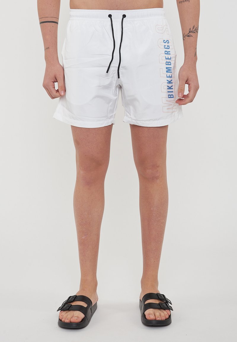 Witte zwembroek met zwarte trekkoord, met de tekst "BIKKENBERGS" in verloop van blauw en beige. Lichtgewicht, gladde stof, lengte tot de knie.