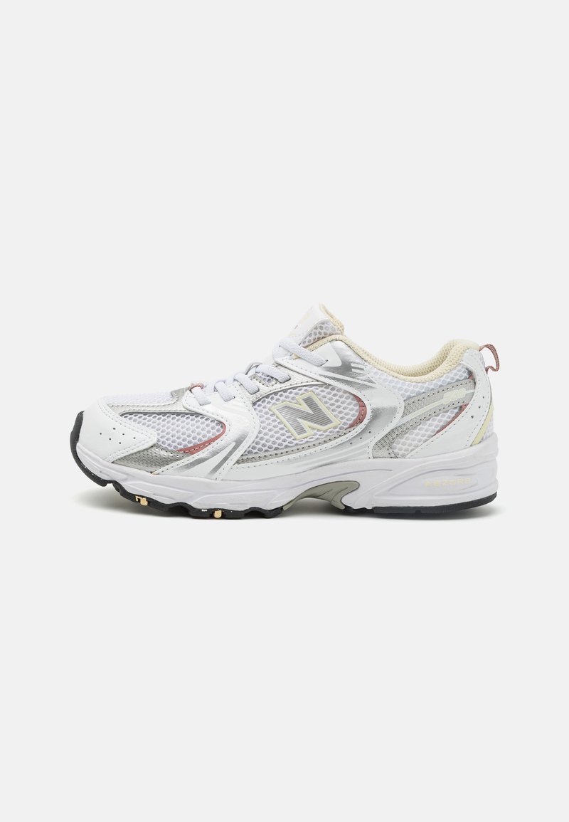 White athletic shoes with mesh upper, silver and beige accents, textured sole, logo on the side, and lacing system for secure fit.