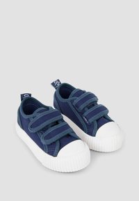 Sneakers in tela blu marina con strap in velcro, punta e suola in gomma bianca, tessuto testurizzato e un piccolo tag con logo sul tallone.