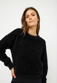 Maglione nero, morbido e peloso, con scollatura rotonda, maniche lunghe e orlo corto. Tessuto soffice e design minimalista.