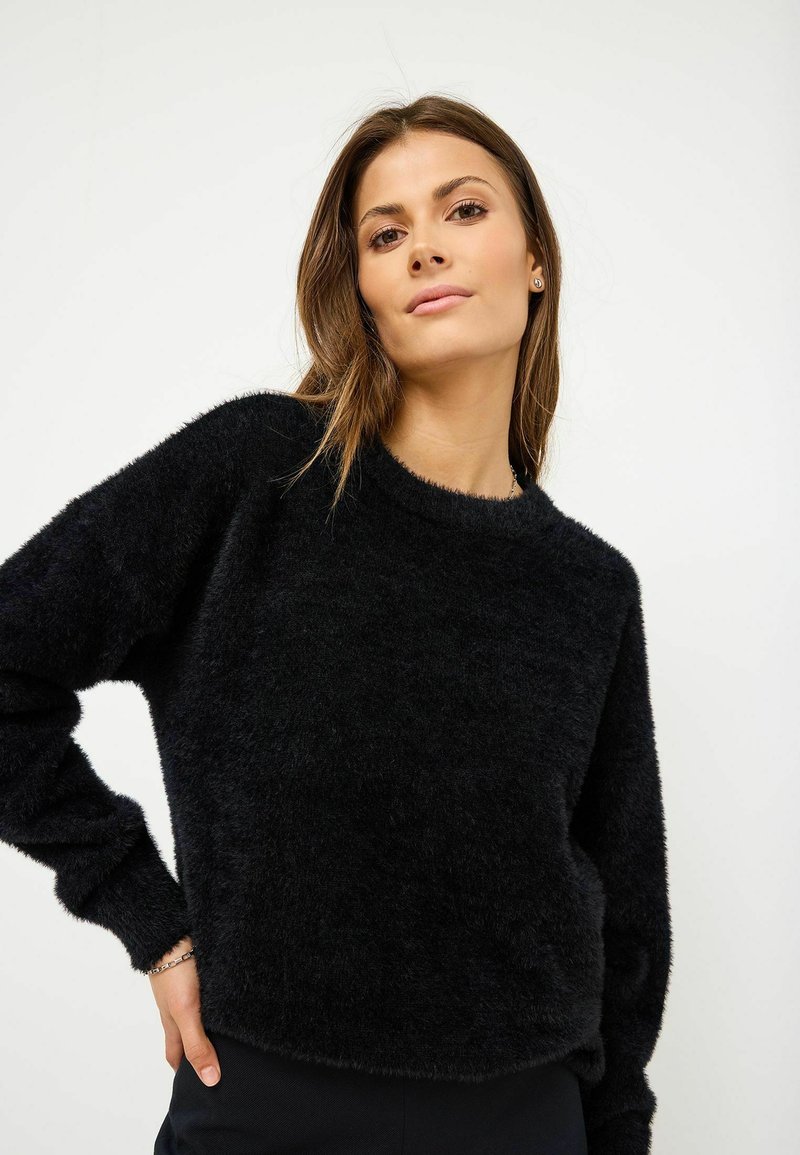 Maglione nero, morbido e peloso, con scollatura rotonda, maniche lunghe e orlo corto. Tessuto soffice e design minimalista.