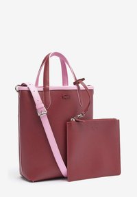 Sac cabas bordeaux avec poignées roses et bandoulière ajustable, accompagné d'une pochette amovible assortie avec fermeture éclair.