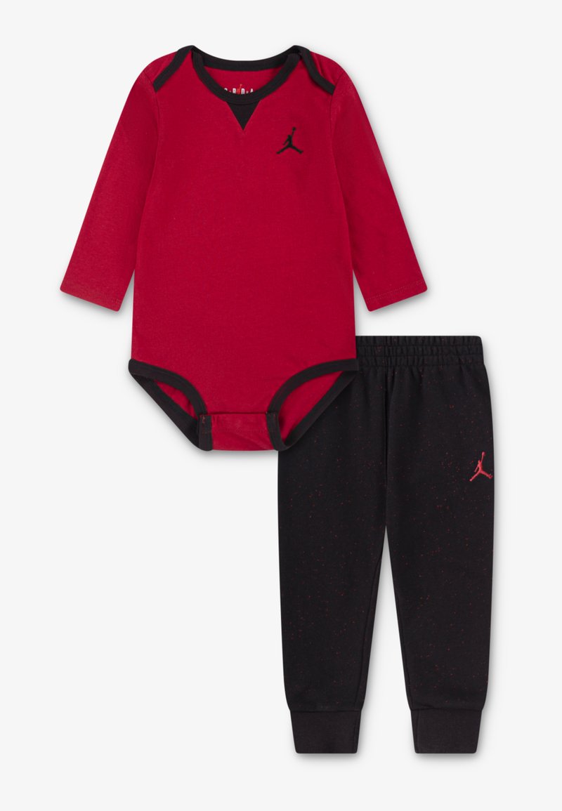 Body rouge à manches longues avec des accents noirs et un logo Jordan, associé à un pantalon de survêtement noir avec des éclaboussures rouges et un logo sur la jambe.