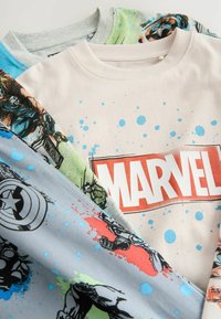 Drei übereinanderliegende Grafik-T-Shirts: eines in Creme mit rotem "MARVEL"-Logo, eines in Blau mit bunten Spritzern und eines in Grau mit Comicfiguren.