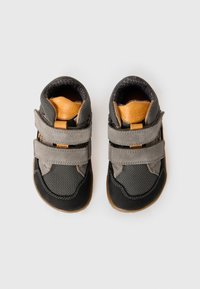 Child's gray and black sneakers with gray double velcro straps and tan leather accents, viewed from above on a white background.