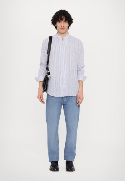 Prugasta srajca s gumbom v svetlo modri in beli barvi, v kombinaciji s svetlo modrimi kavbojkami. Nosijo črno torbo z naramnico. Črne čevlje. Preprost dizajn.