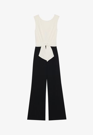 Valge ilma varrukateta topp kaheksase vööga ja mustad lai jalad püksid, valminud pehmest kangast, mis omab siledat tekstuuri ja kontrastset värvigammat.