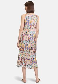 Robe maxi avec un motif floral multicolore, fabriquée en tissu léger au toucher doux, sans manches et de coupe longue jusqu'aux chevilles.