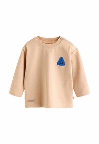 Világos bézs színű, hosszú ujjú ing, puha pamutból készült. Az elején egy kék kötött háromszög folt található, illetve egy kis címke a szegélyén.