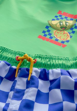 Zeleno kopalno majico z grafičnim potiskom in modre karo kopalke. Ima vrvico s rumenimi poudarki in elastični pas.