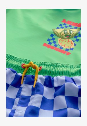 Zeleno kopalno majico z grafičnim potiskom in modre karo kopalke. Ima vrvico s rumenimi poudarki in elastični pas.