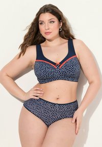 Lahja sinivalkoinen bikinitsetti laajoilla olkaimilla ja kontrastivärisellä korallivärillä. Rintaliiveissä on koristeellinen nauha keskellä, joka tarjoaa täyden peittävyyden.