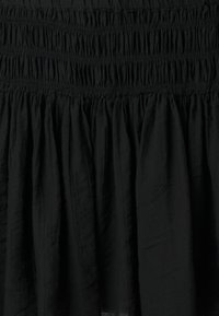 Μαύρη φούστα με σούρες στη μέση και ροή στη φαρδιά κάτω περιοχή. Φτιαγμένη από ελαφρύ ύφασμα με απαλή υφή.