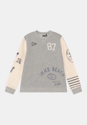 Grå og cremefarvet langærmet sweatshirt med "87," "IKKS Beach," striber på højre ærme samt forskellige tekster og logotryk på front og ærmer.