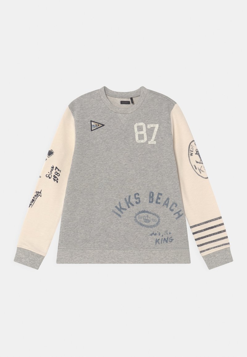 Sweat-shirt à manches longues gris et crème avec "87", "IKKS Beach", rayures sur la manche droite, et divers textes et logos imprimés sur le devant et les manches.