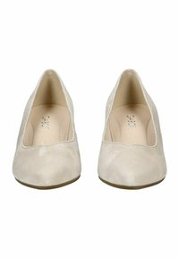 Zapatos de tacón alto de ante beige con punta redondeada y diseño de corte bajo, que presentan una textura suave y un logotipo grabado sutil en el interior.