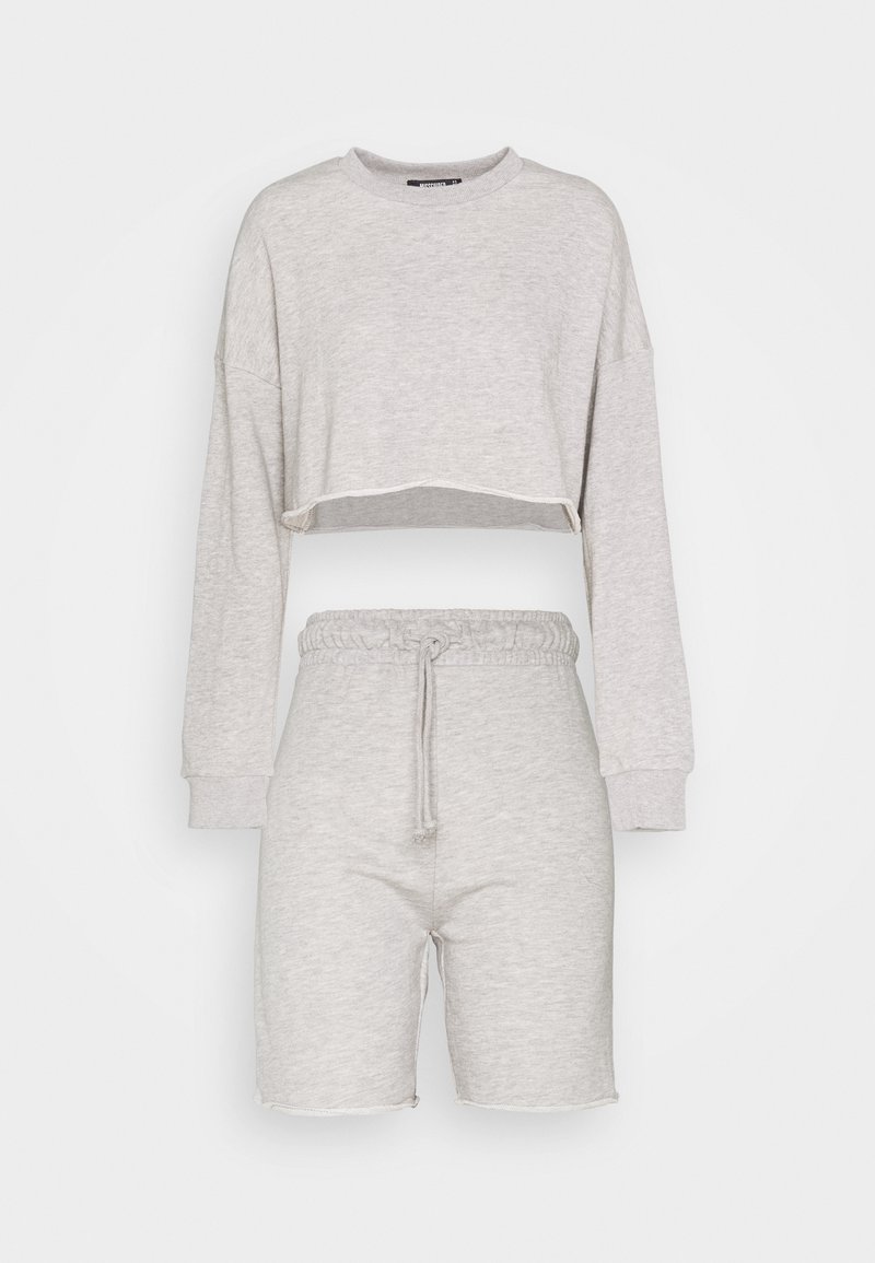 Tenue deux pièces gris clair avec sweat court à manches longues et short taille haute à cordon assorti sur fond uni.