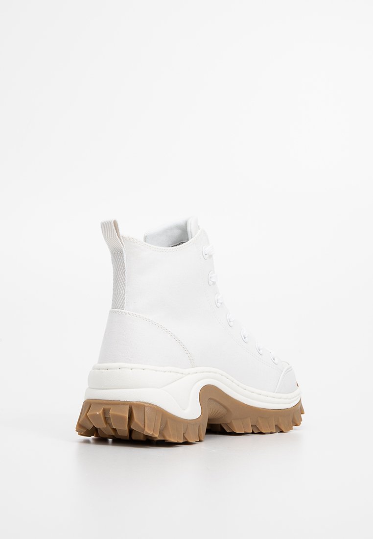 Sneaker alte bianche con suola in gomma testurizzata, parte superiore in tessuto morbido e una suola in gomma naturale spessa e prominente. Presentano un design con lacci.