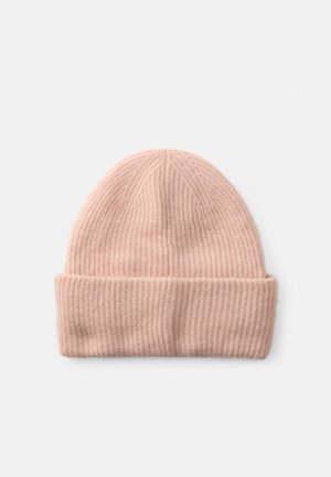 Bonnet en tricot côtelé doux de couleur rose pâle avec un revers, posé sur un fond blanc uni.