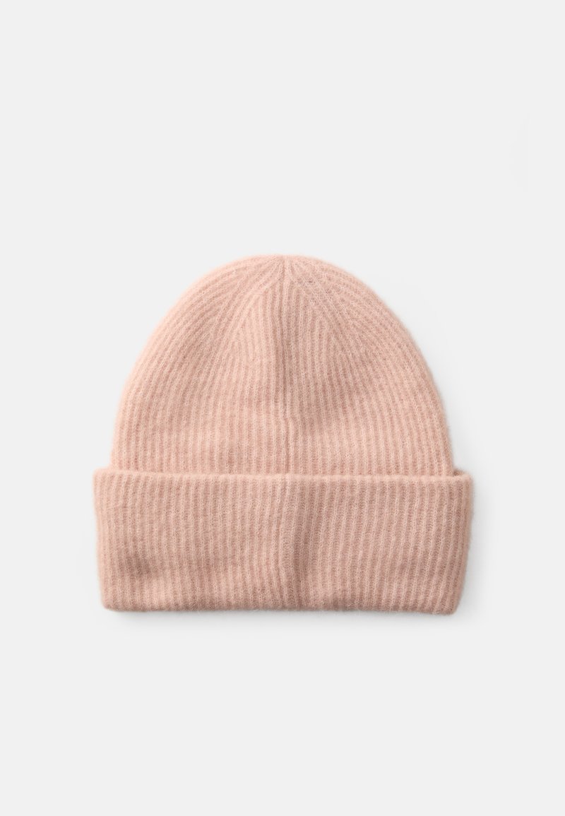 Bonnet en tricot côtelé doux de couleur rose pâle avec un revers, posé sur un fond blanc uni.