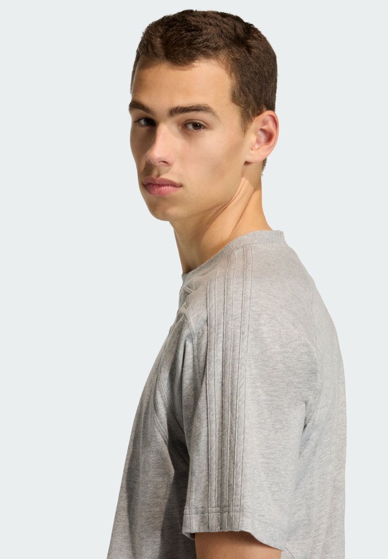 Gray short-sleeve t-shirt with a ribbed crew neck and three vertical stripes along the shoulders. Soft fabric with a smooth texture.