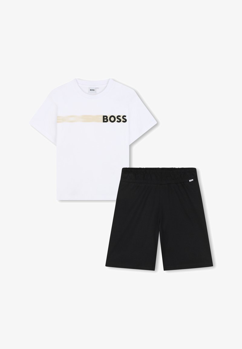 Fehér, rövid ujjú póló arany csíkkal és fekete "BOSS" felirattal. Fekete, gumis derekú, egyenes szabású rövidnadrág.