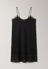 Robe nuisette noire avec fines bretelles spaghetti, bordure en dentelle le long du décolleté et de l'ourlet, suspendue contre un fond clair uni.