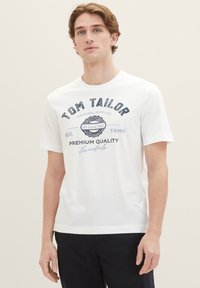 White cotton t-shirt with short sleeves, featuring navy blue printed text and a badge design on the front. Simple crew neck style.