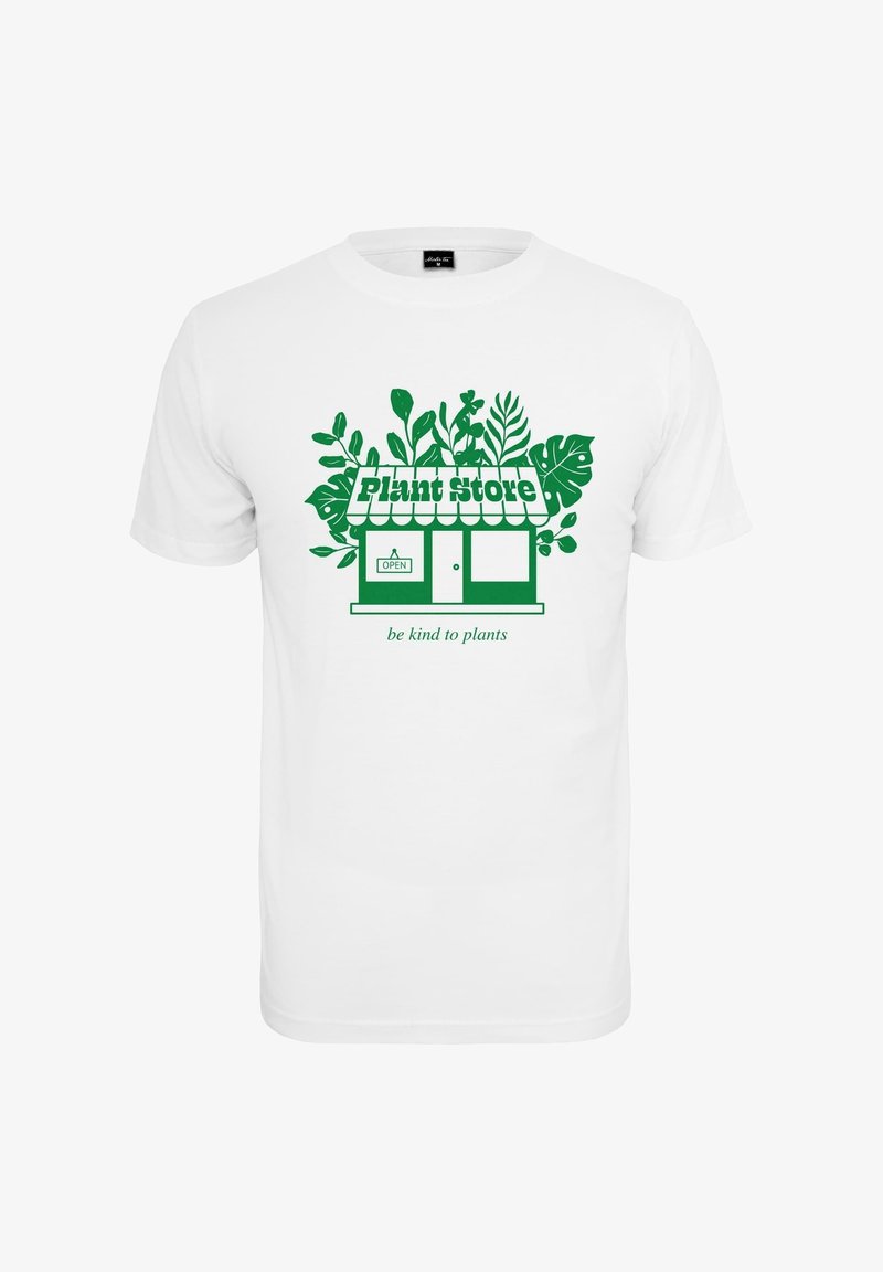 Biała koszulka z zieloną grafiką przedstawiającą witrynę sklepu z roślinami, otoczoną liściastymi roślinami, oraz napisem "bądź miły dla roślin" poniżej.
