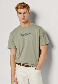 Lysegrøn bomuld t-shirt med rund hals og korte ærmer, med "Pepe Jeans London" logo trykt i mørkegrøn på tværs af brystet.