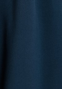 Donkerblauwe textuurstof met een canvasachtige weving, die een gladde oppervlakte en een lichte glans vertoont, geschikt voor bekleding of kleding.