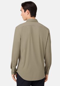 Lange mouwen shirt in gedempt olijfgroen, gemaakt van gladde stof. Heeft een klassieke kraag, knoopmanchetten en een rechte zoom.