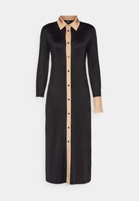 Robe midi noire à manches longues avec col beige clair, patte de boutonnage et une manchette, présentant une texture côtelée verticale.