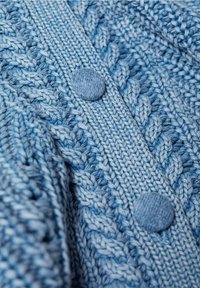 Cardigan bleu tricoté avec un motif texturé, deux boutons ronds en tissu et une patte côtelée, offrant un aspect doux et confortable.