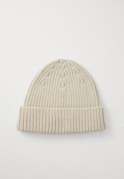Caciula tricotată de culoare bej deschis; are o textură ribbină și un manșon pliat. Design simplu și elegant, potrivit pentru purtatul în sezonul rece.