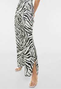 Černobílé kalhoty s pruhy zebry, široké s rozparky po stranách, vyrobené z lehkého materiálu, s hladkým povrchem a uvolněným střihem.