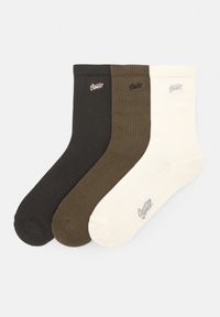 Tre par sokker: mørkebrun, olivengrøn og creme. Ribbet tekstur med et logo på hver sok.