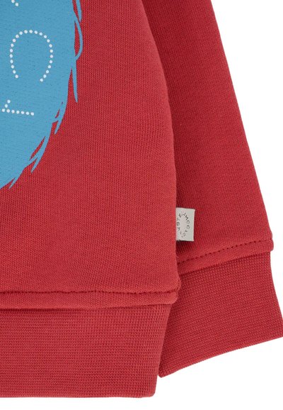 Czerwona bawełniana bluza z nadrukiem graficznym w kolorze niebieskim i białym tekstem w kropki. Zawiera małą metkę przy dolnym szwie. Tkany materiał o teksturowanej strukturze.