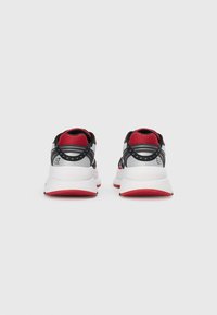 Sapatilhas desportivas pretas e vermelhas com um cabedal de malha texturizada, suporte acolchoado para o tornozelo e solas brancas com realces em vermelho.