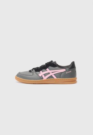 Grå sportssko med pink striber, sorte snørebånd og brun sål med mærket Asics og teksten Skyhand på siden.