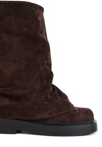 Stivale in suede marrone scuro, a metà polpaccio, con punta arrotondata e spessa suola in gomma nera, mostrato di lato su uno sfondo bianco.