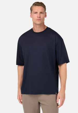 Camiseta de manga corta azul marino hecha de tejido suave. Presenta un escote redondo y un corte relajado. Etiqueta de marca sutil en el dobladillo.