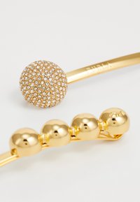 Gold bracelets with one featuring a round cluster of small clear crystals and the other adorned with five smooth gold beads.