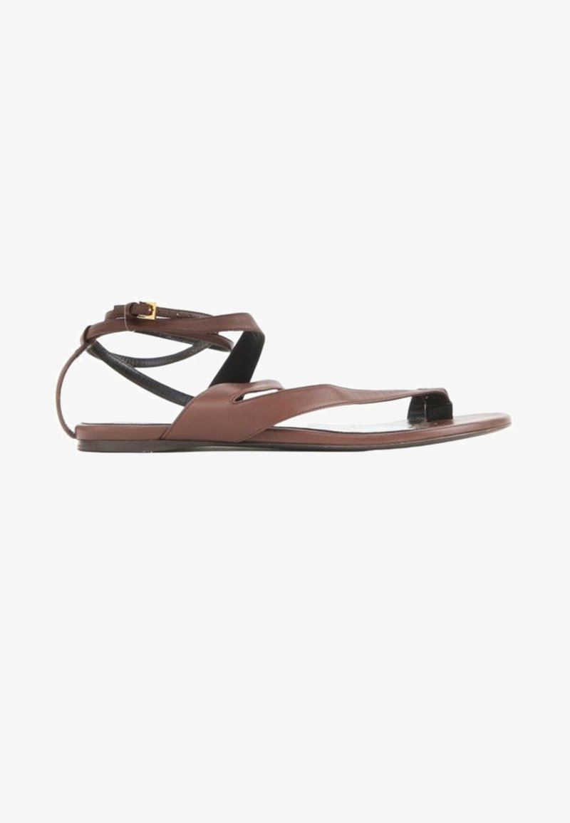 Sandale plate en cuir marron avec fines brides à la cheville et boucle dorée, comportant une boucle pour l’orteil et un design ouvert.