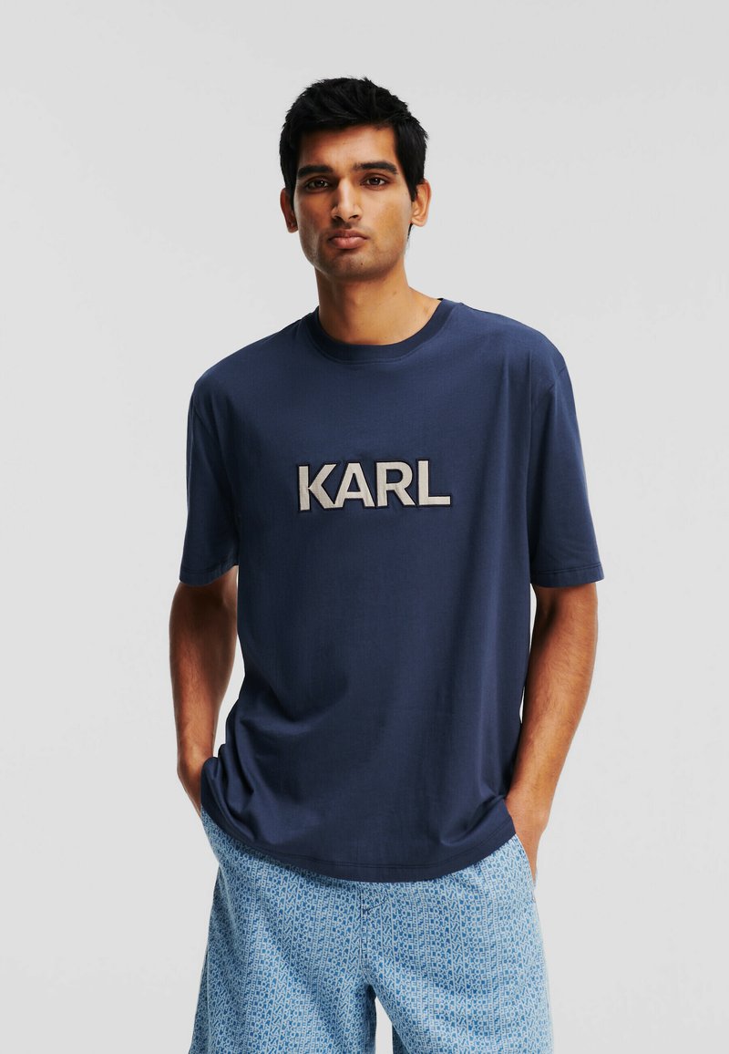 T-shirt à manches courtes bleu marine avec un logo "KARL" en broderie grise. Tissu doux avec une coupe décontractée.