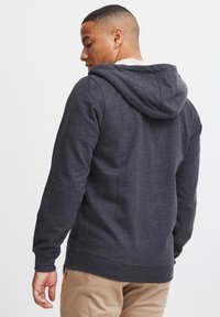 Sudadera gris oscuro hecha de una tela suave, con capucha ajustable, puños y dobladillo acanalados, un acabado texturizado y detalles mínimos.