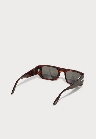 Gafas de sol carey con lentes rectangulares, patillas delgadas y un acento plateado en las varillas. Acabado texturizado en colores marrón y ámbar.