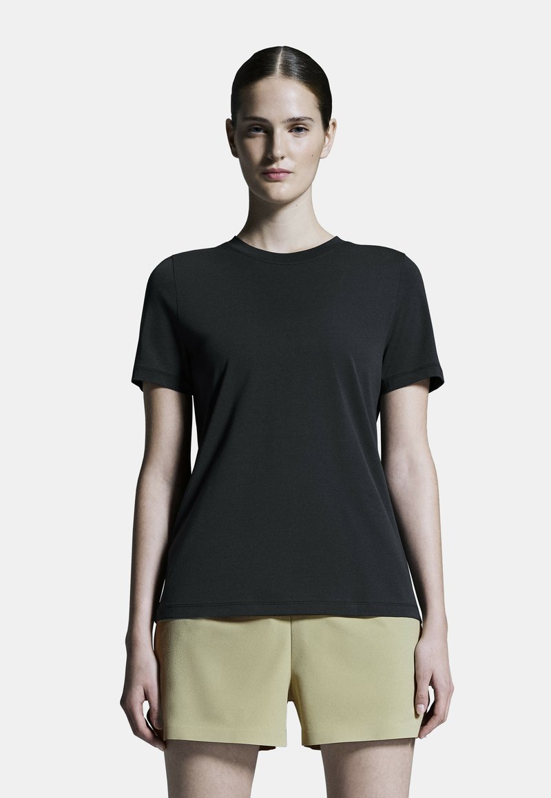 T-shirt noir à manches courtes avec col rond, fabriqué en tissu lisse, associé à un short jaune clair au design structuré.
